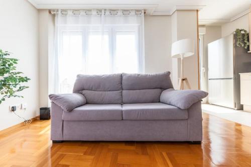 a couch in a living room with a large window at Charming Coastal Apartment Steps from the Beach in San Juan de la Arena