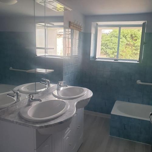 La salle de bains est pourvue de 3 lavabos et d'une fenêtre. dans l'établissement Gîte le temps de vivre, à Pressac