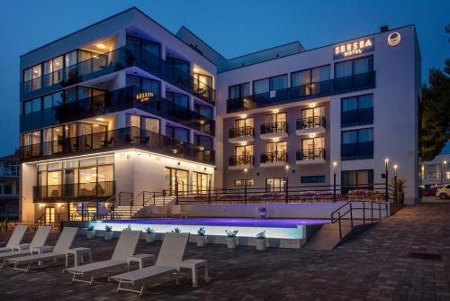 a hotel with a swimming pool in front of a building at SeeSea Hotel in Vodice