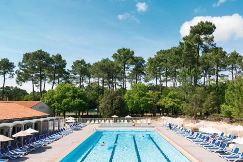 - une piscine avec des chaises et des arbres bleus dans l'établissement Belambra Clubs La Palmyre - Les Mathes, aux Mathes