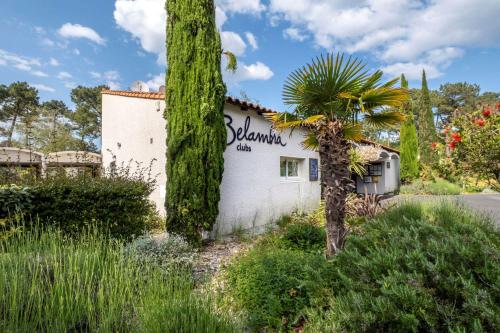 un bâtiment blanc avec un palmier devant dans l'établissement Belambra Clubs La Palmyre - Les Mathes, aux Mathes