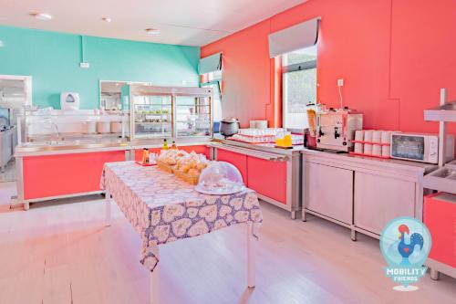 a brightly colored kitchen with a table with fruit on it at Mobility Friends Hostel in Barcelos