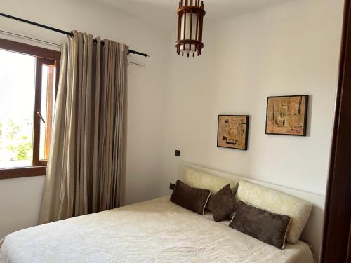 a bedroom with a bed with two pillows and a window at Apartement cabo in Tétouan