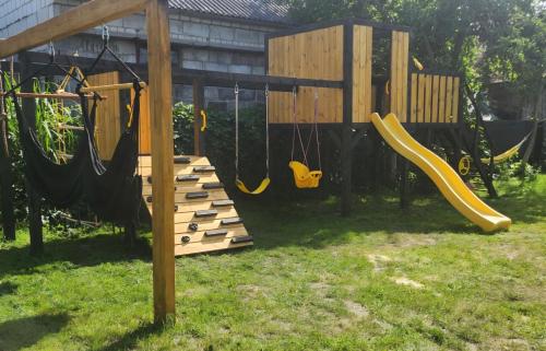 a playground with a slide and swings in a yard at Noclegi w Nieliszu, dom blisko plaży in Nielisz