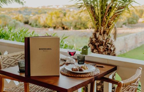 a table with a plate of food and a glass of wine at Binissaida Boutique Hotel in Es Castell