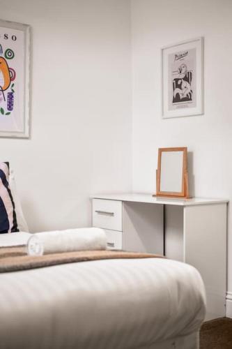 a white bedroom with a bed and a desk at Huge Duplex in Great Location in Heaton