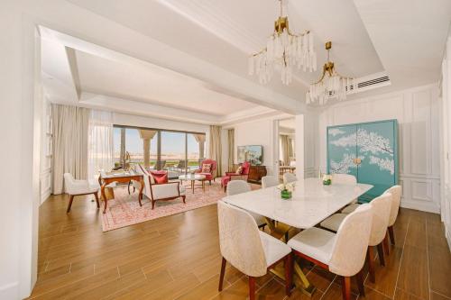 a dining room and living room with a table and chairs at Royal Saray Resort in Manama