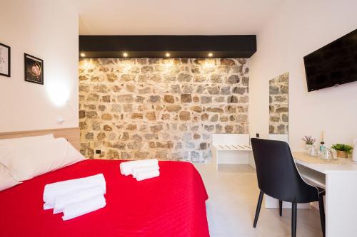 a red bed in a room with a stone wall at Affittacamere Casa Concia in Tortolì