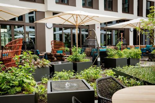 an outdoor garden with tables and chairs and umbrellas at Motel One Köln-Messe in Cologne