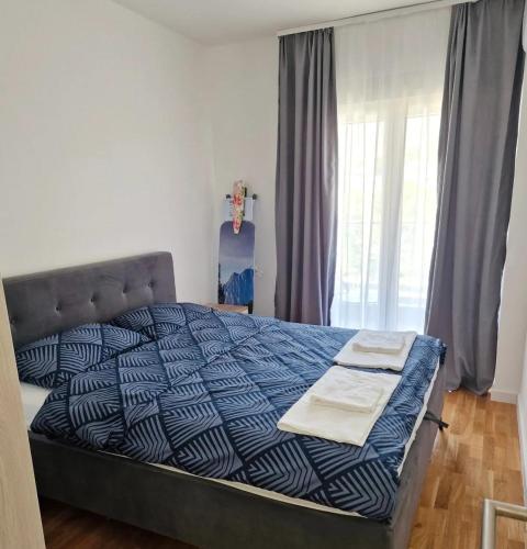 a bedroom with a bed with a blue and white comforter at Apartman BOSS Lux in Trebinje