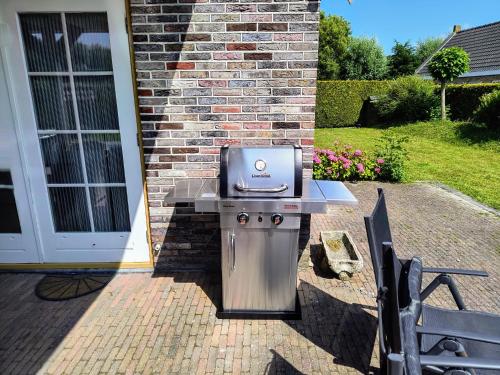 a grill sitting on a patio next to a building at Gemütliches Ferienhaus mit beheiztem Pool, Garten und überdachter Terrasse in Tzummarum