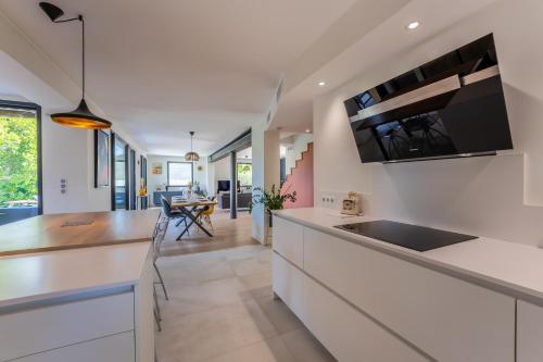 une cuisine avec comptoirs blancs et comptoir dans l'établissement Piscine, clim, terrain de pétanque et jeux enfants, à Montpellier