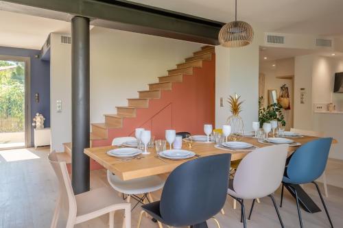 une salle à manger avec une table et des chaises et un escalier dans l'établissement Piscine, clim, terrain de pétanque et jeux enfants, à Montpellier