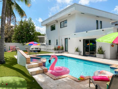a swimming pool with two pink flamingos in front of a house at Villa Palma - Prime Location, Pool, Game Room, Outdoor Kitchen in Miami