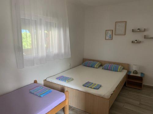 a small bedroom with two beds and a window at Vila Andja, Apartmani i Sobe in Krašići