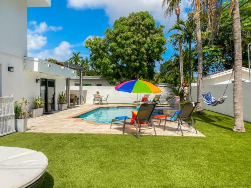 a patio with chairs and an umbrella next to a pool at Villa Palma - Prime Location, Pool, Game Room, Outdoor Kitchen in Miami