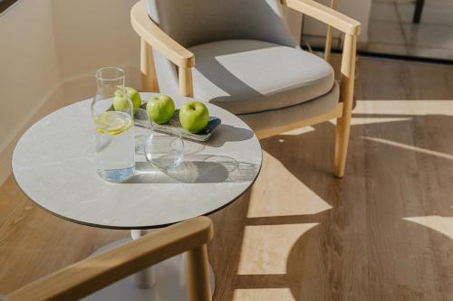 a glass table with a bowl of apples and a glass of water at Alion Beach Hotel in Ayia Napa