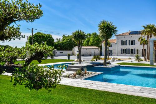 une piscine dans une cour avec des palmiers et un bâtiment dans l'établissement Chez Dyl's Villa tout confort, à Saint-Georges-du-Bois