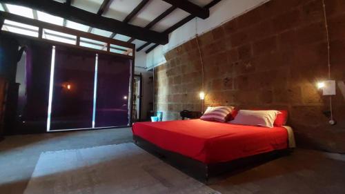 a bedroom with a red bed with a brick wall at Libera Mente Civita in Bagnoregio