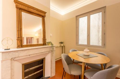 une salle à manger avec une table et un miroir au-dessus d'une cheminée dans l'établissement Suite Comedie - Premiere conciergerie, à Montpellier