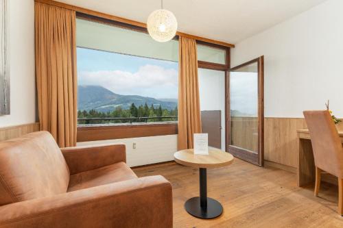 a living room with a couch and a large window at Appartementhaus Dachsteinblick mit Indoorpool und Sauna in Bad Goisern