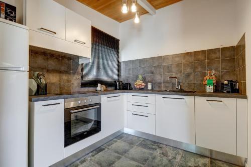une cuisine avec des armoires blanches et un évier dans l'établissement A Casetta - Maison climatisée avec piscine, à Belgodère