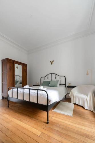 - une chambre blanche avec 2 lits et du parquet dans l'établissement LE COCON ART - Proche Thermes - Centre ville - Au calme, à Vichy