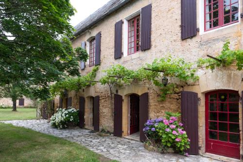 an old stone building with flowers and windows at Le Bel Prat in Domme