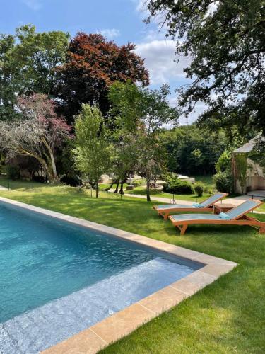- une piscine avec 2 salons et des bancs dans une cour dans l'établissement Château de la Huberdière, à Nazelles-Négron