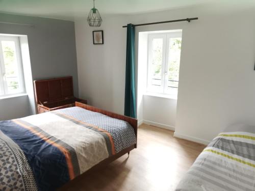 une chambre avec deux lits et deux fenêtres dans l'établissement Le moulin mallat mazeyrat d allier 43300, à Mazeyrat-d'Allier