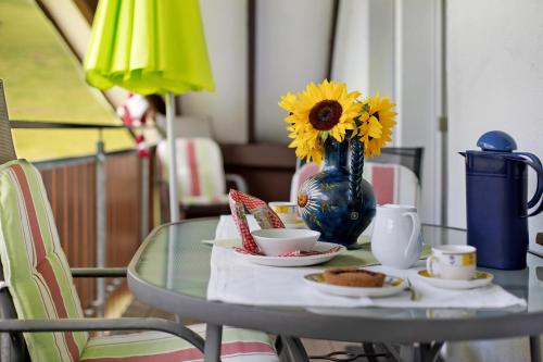 a glass table with a vase with sunflowers on it at Sport Rees - Ferienwohnung Melanie in Oberried