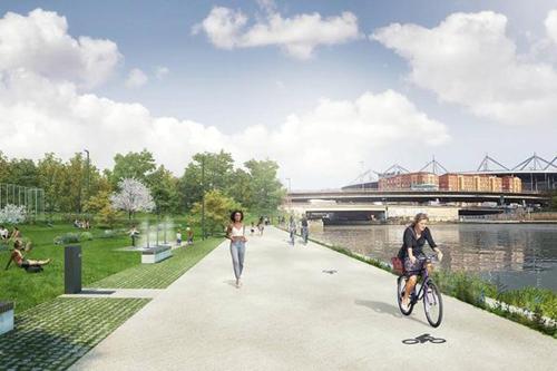 a woman riding a bike on a path next to a river at Hôtel du Parc Canal - Stade de France in Saint-Denis