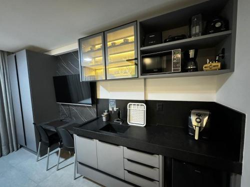 a kitchen with a black counter top and a sink at Get By Side - Jardim Oceania in Tambaú