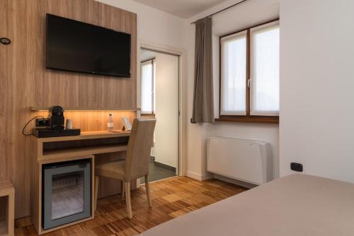 a hotel room with a desk and a television on the wall at Residence Al Frantoio in Arco