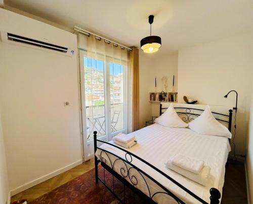 une chambre avec un lit avec des draps blancs et une fenêtre dans l'établissement Appartement proche Monaco , 600m de la plage, à Roquebrune-Cap-Martin
