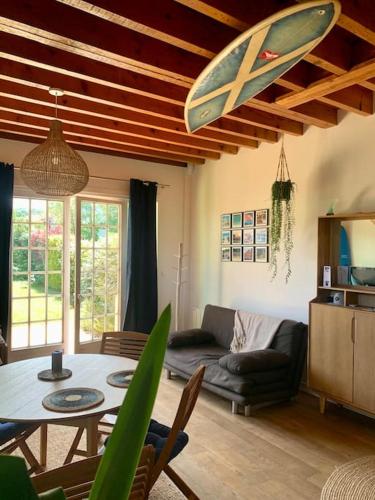 un salon avec une table et une planche de surf au plafond dans l'établissement Wissant, petite maison avec jardin proche mer, à Wissant
