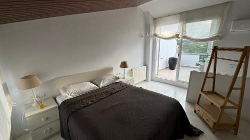a bedroom with a bed and a window and a ladder at Casa Adosada S'Agaró in S'Agaro
