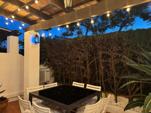 a patio with a black table and white chairs at Casa Adosada S'Agaró in S'Agaro