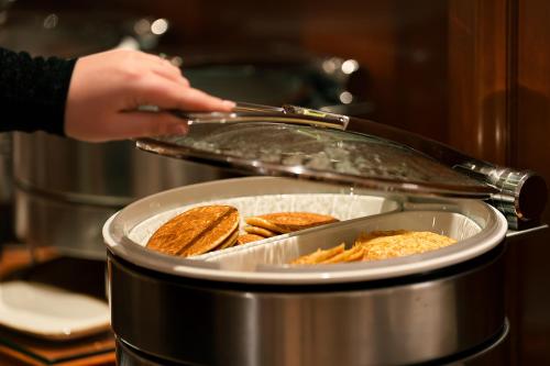 a person is putting food in a pan at Hôtel Château Frontenac in Paris
