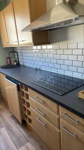 une cuisine avec des armoires en bois et un comptoir noir dans l'établissement La Canopée - Famille - 4 pers, au Havre