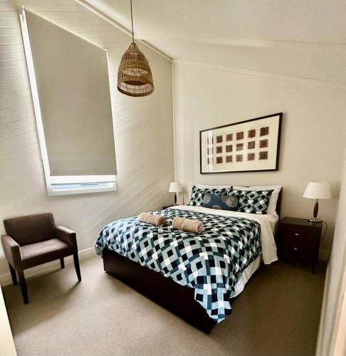 a bedroom with a black and white bed and a chair at 6 Whitecrest Great Ocean Road Resort - Ocean View in Apollo Bay