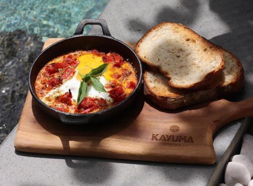 a bowl of food on a wooden board with toast at Kayuma Villas Lombok in Selong Belanak