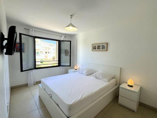 une chambre blanche avec un lit et une fenêtre dans l'établissement Joli T2 idéalement situé, à Propriano