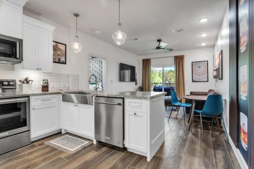 a kitchen with white cabinets and a table with blue chairs at Whiskey River - Texas Music Theme in Historic Gruene, Riverfront on the Guadelupe River in New Braunfels