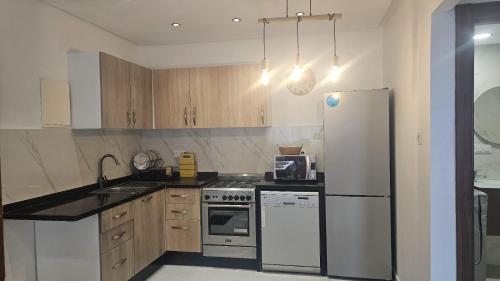 a kitchen with a white refrigerator and a sink at malaga mansouria cosy moderne studio 1 ch salon canape lit moderne in Mansouria