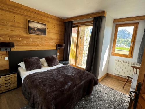 une chambre avec un grand lit dans une pièce aux murs en bois dans l'établissement Bel appartement 4 pièces avec piscine, jacuzzi, sauna, animaux admis - FR-1-181-2818, à La Plagne Tarentaise