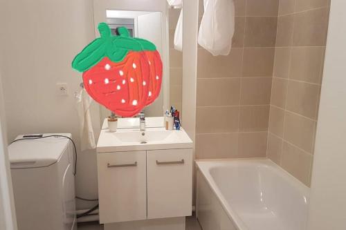 une salle de bain avec un lavabo et une fraise géante sur le miroir dans l'établissement Appartement idéalement situé à Evry-Courcouronnes, Évry-Courcouronnes