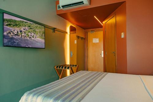 a bedroom with a bed and a tv on the wall at Verdegreen Hotel in João Pessoa