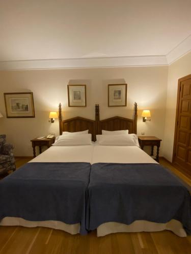 a bedroom with a large bed with white sheets at Parador de Vilalba in Villalba
