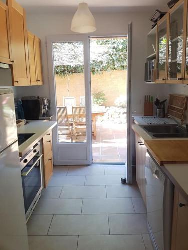 une cuisine avec une porte s'ouvrant sur une terrasse. dans l'établissement Le Cocon du sud proche plage Renecros, à Bandol